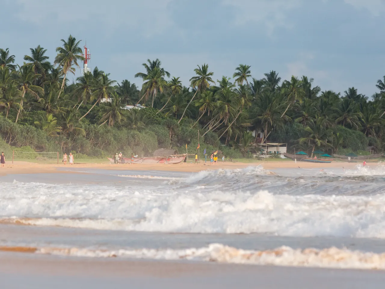 Waves rolling onto a palm-lined beach along Sri Lanka's tropical coast.