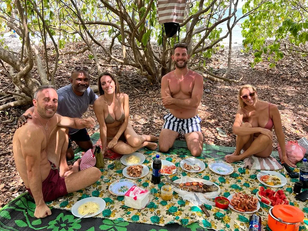 Tour guide Romesh with guests at a beach picnic featuring fresh fish during a tour of Sri Lanka.