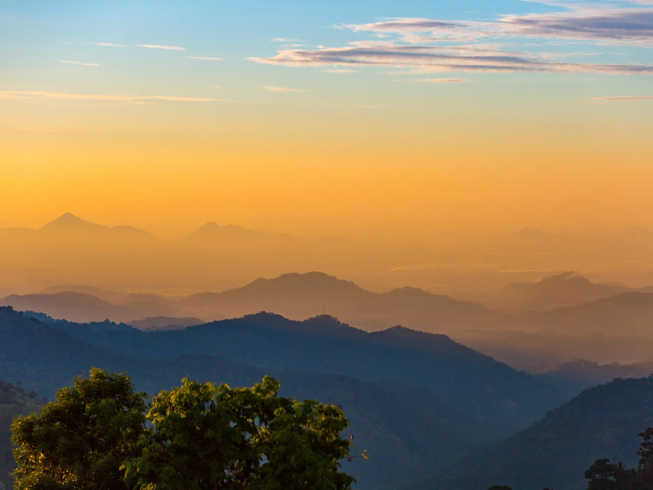 Sunset over tiered mountain silhouettes from Little Adam's Peak in the Central Highlands of Sri Lanka.